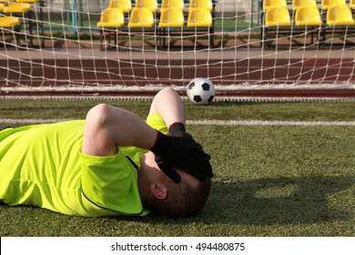 Football player covers own face. The Goalkeeper during the game missed the ball in gate. Soccer player after losing, on a bright sunny day in the great outdoors. Depressed, failure, stress concept. - Powered by Shutterstock