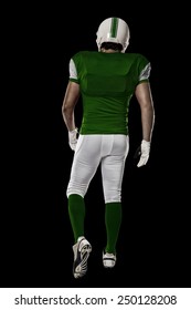Football Player With A Green Uniform Walking, Showing His Back On A Black Background.