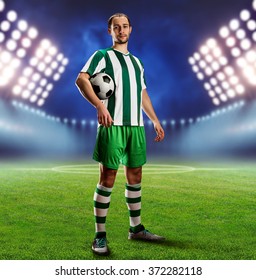 Football Player Holding A Ball On The Football Ground At Night