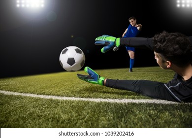 Football player kick ball and goalkeeper try to catch the ball and save goal - Powered by Shutterstock