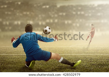 Football player kick ball and goalkeeper try to catch