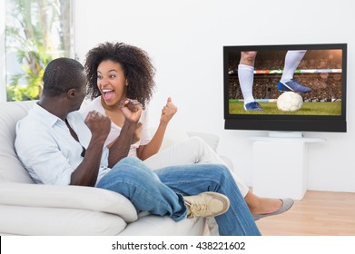 Football player kicking ball against couple sitting on couch together watching tv - Powered by Shutterstock