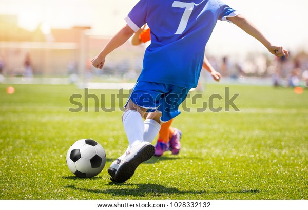 Football Player Kicking Ball on Grass Pitch. Soccer\
Striker Scoring Goal