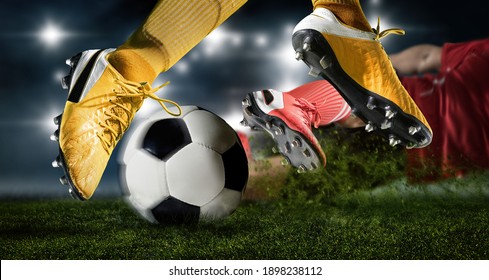 Football Player Man In Action On Dark Arena Background. Soccer Player Making Sliding Tackle