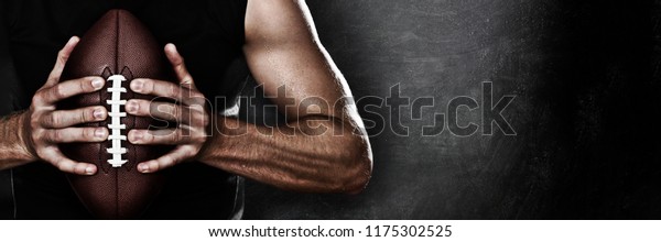Football player man player holding american\
football on black blackboard texture background with copy space for\
text or design. Panoramic\
banner.