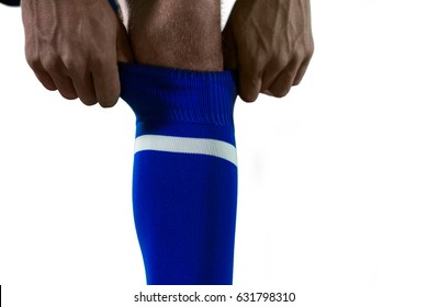 Football Player Pulling His Socks Up Against White Background