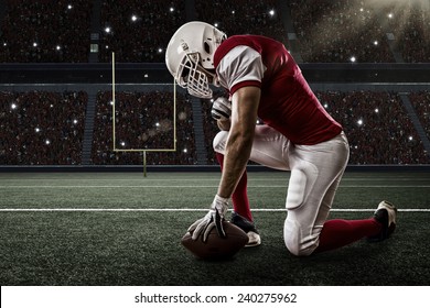 Football Player with a red uniform on his knees, on a Stadium. - Powered by Shutterstock