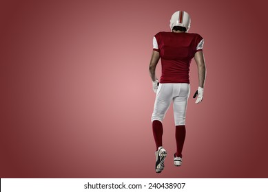 Football Player With A Red Uniform Walking, Showing His Back On A Red Background.