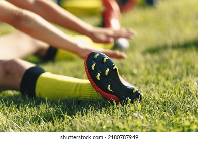 Football Player Stretches Sitting on Grass Pitch. Stretching Session After Workout For Footballers. Player in Soccer Cleats and Socks - Powered by Shutterstock