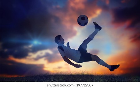 Football player in white kicking against green grass under dark blue and orange sky - Shutterstock ID 197729807