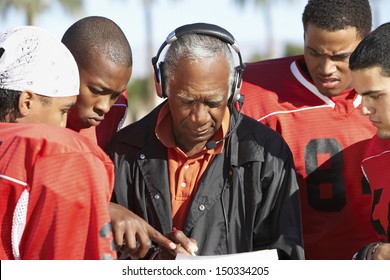 Football Players And Coach Discussing Strategy Together