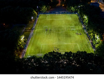 Football Players Running Around The Football Field. Night Workout. Preparation For The Match. Aerial Shot With A Drone From A Altitude