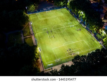 Football Players Running Around The Football Field. Night Workout. Preparation For The Match. Aerial Shot With A Drone From A Altitude