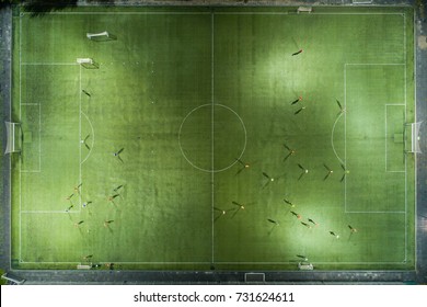 Football Players Running Around The Football Field. Night Workout. Preparation For The Match.  Aerial Shot With A Drone From A Altitude