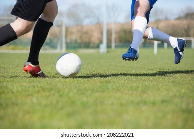 Football players tackling for the ball on pitch on a clear day - Powered by Shutterstock