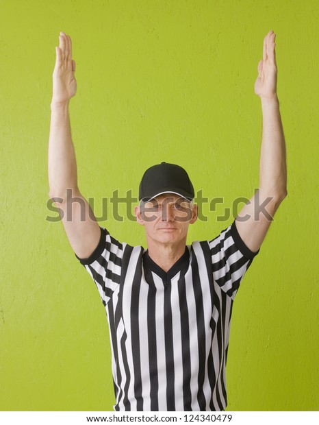 Football referee against green background\
signaling a touchdown, three quarter\
length,