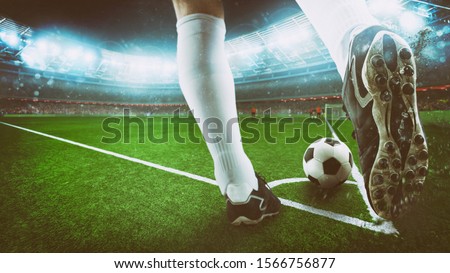Football scene at night match with close up of a soccer shoe hitting the ball from corner kick