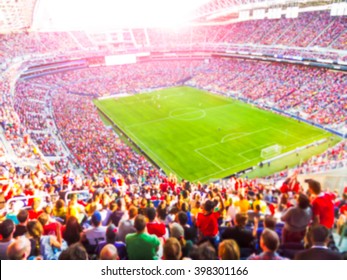 Футбольные болельщики радуют свою команду и празднуют гол на полном стадионе под открытым небом с ярким световым лучом - размытым изображением.