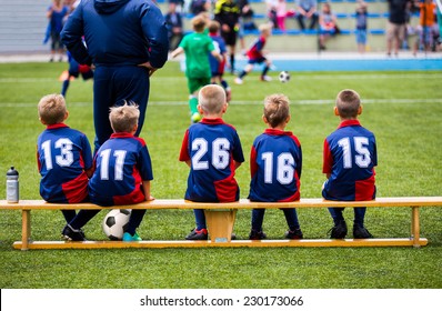 Football Soccer Match For Children. Kids Waiting On A Bench.