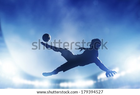 Football, soccer match. A player shooting on goal performing a bicycle kick. Lights on the stadium at night.