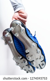 Football Soccer Player Holding Football Boots Cleats In Hand On White Background With Copy Space.