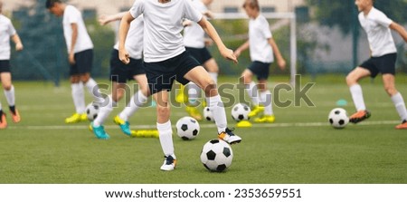 Football soccer school for youth boys. Group of teenage boys kicking soccer balls during a training session. Kids play soccer training games on the training pitch. School kids in white jersey shirts