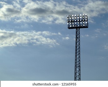 a football stadium floodlight silhouetted against a dusky blue sky - Powered by Shutterstock