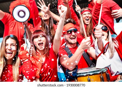 Football Supporter Fans Cheering With Confetti Watching Soccer Match At Stadium Tribune - Young People Group With Red T-shirt Having Excited Fun On Sport Cup Championship - Bright Vivid Filter