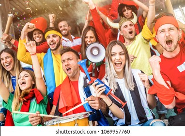 Football supporter fans friends cheering and watching soccer cup match at intenational stadium - Young people group with multicolored t-shirts having excited fun on sport world championship concept