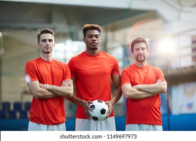 Football team of three young men in red uniform standing on stadium or field for game - Powered by Shutterstock