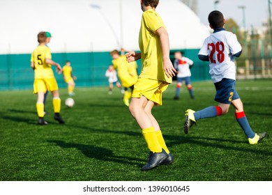 Football Teams Boys In Yellow White Sportswear Play Soccer On The Green Field. Dribbling Skills. Team Game, Training, Active Lifestyle, Hobby, Sport For Kids Concept