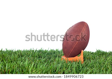 Football tee on green grass waiting for a kick off. White background for placement of copy.