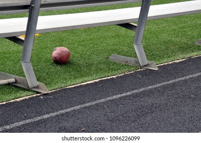 A Football Underneath A Bench On The Sideline Of A Football Field