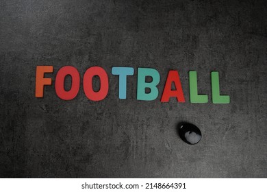 Football Word Spelled On A Black Reflective Textured Background In A Studio Lighting Setup