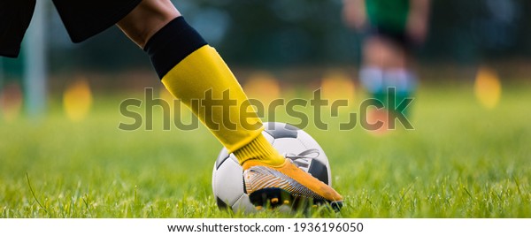 Footballer Kicking Ball Moment. Closeup\
of Soccer Players Leg Moving Toward Soccer Ball. Athlete in Soccer\
Cleats Running and Kicking Ball on Grass Turf\
Field