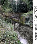 Footbridge across canal to the remains of the glazing works in the Oare Gunpowder Works Country Park, Faversham, Kent, UK.