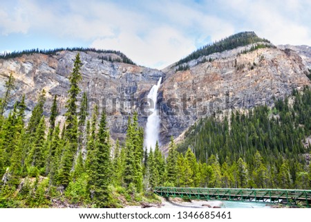 Footbridge across Kicking Horse River to the powerful Takakkaw Falls in Yoho National Park near Field, British Columbia, Canada. The Glacier-fed waterfall is one of the tallest in Canada.