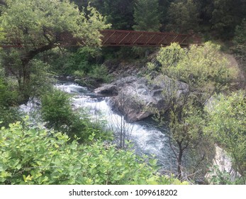 A Footbridge Crosses A Roaring River On A California Gold Country Hiking Trail