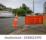 Footpath Closed road sign by the road. Cars travelling on the road. Roadworks in Auckland.