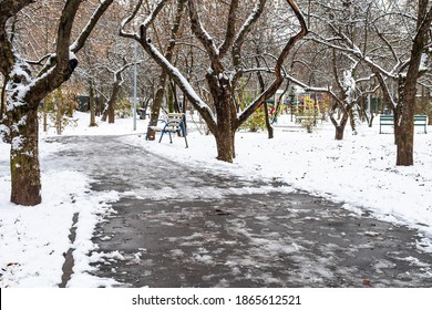 Footpath With The First Melting Snow In Snow-covered City Park On Cold Autumn Day