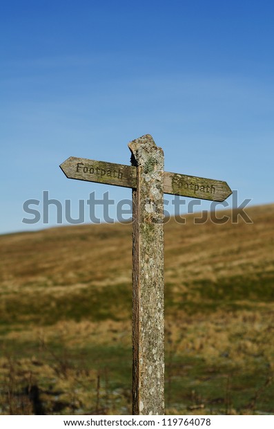 Footpath sign against hill and
sky