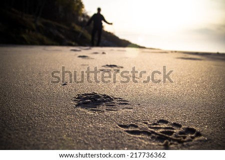 Footprint in the sand and the figure of a man cultivating Nordic walking