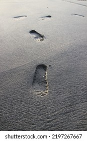 Footprints On Black Sand. Footprints Of A Man Walking Along The Beach To The Sea In The Morning