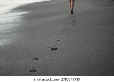 footprints on the black sandy beach bali