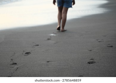 footprints on the black sandy beach bali