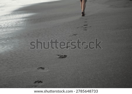 footprints on the black sandy beach bali