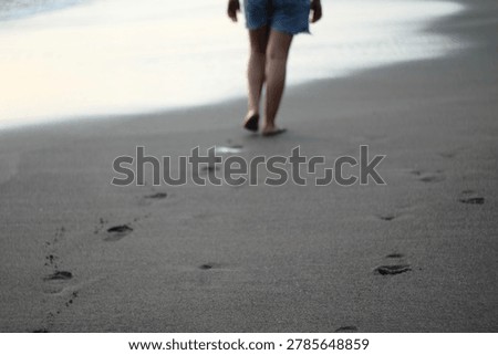 footprints on the black sandy beach bali