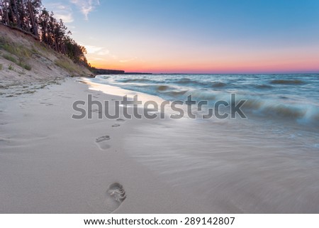 Footprints on the sand at empty sunset beach.