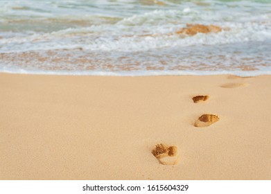 Footprints on the sand leading to the sea.