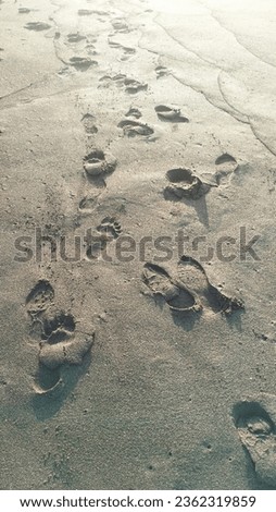 footprints of people visiting Tangtu Beach Bali on the fine black sand at a beautiful sunrise